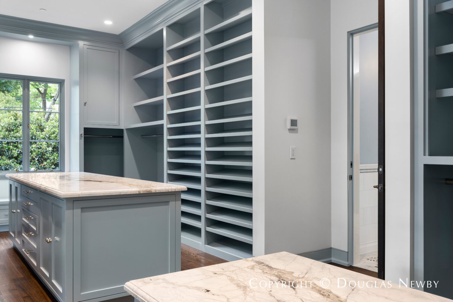 Women's closet with storage islands covered in Aegean Sea marble in this architecturally significant estate home located at 4400 Belfort Place in Highland Park, Dallas, Texas.