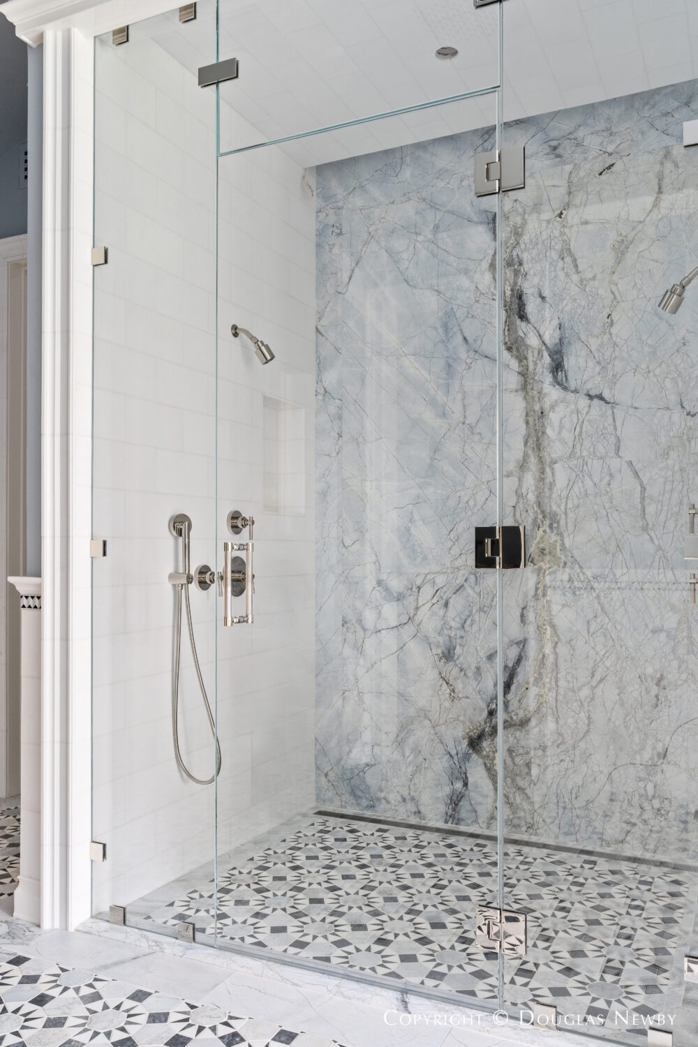 Marble walls and tile floor of large shower in the master bathroom of 4400 Belfort Place, Highland Park, Dallas, Texas.